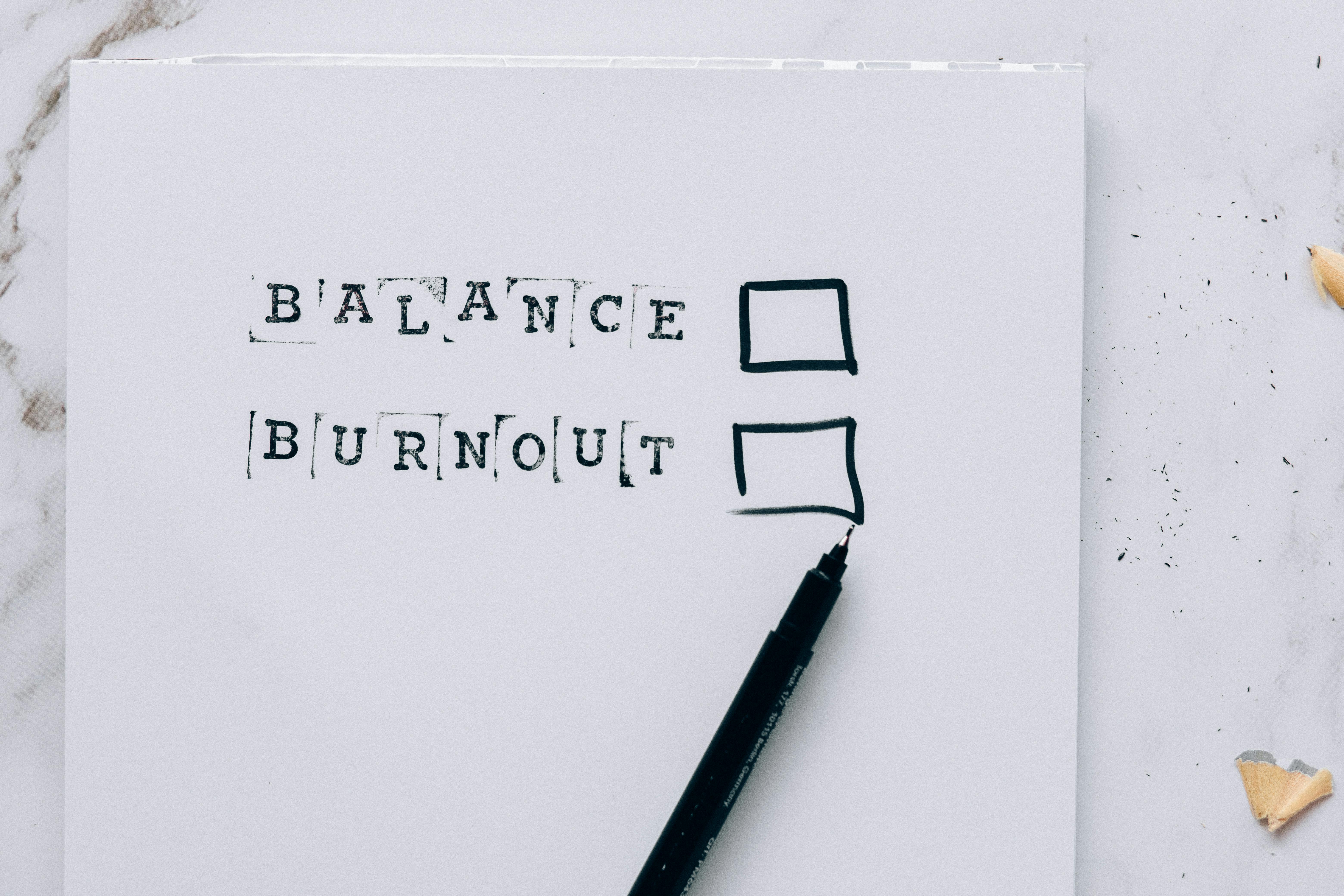 The words Balance and Burnout with check boxes and a pen